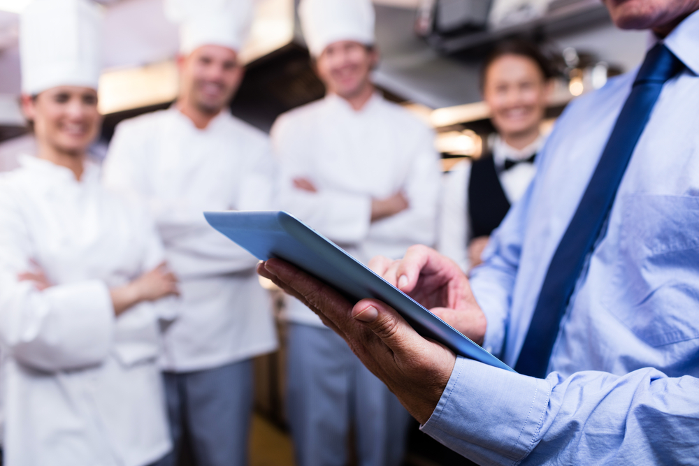Man holding a clipboard in front of chefs